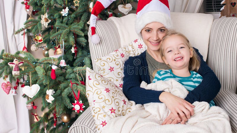 Autentisk familjjulstående framme av xmas-trädet Le modern och dottern på jul royaltyfria bilder