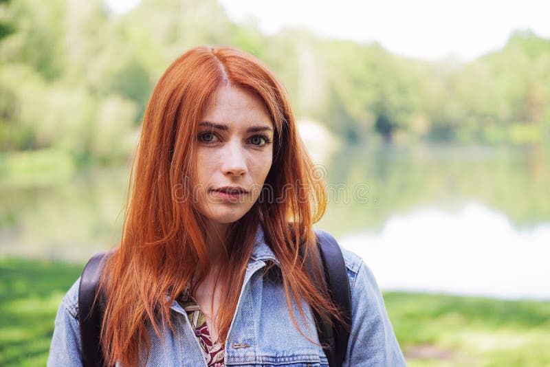 Authentic young woman wearing denim jacket and backpack outdoors on a hike