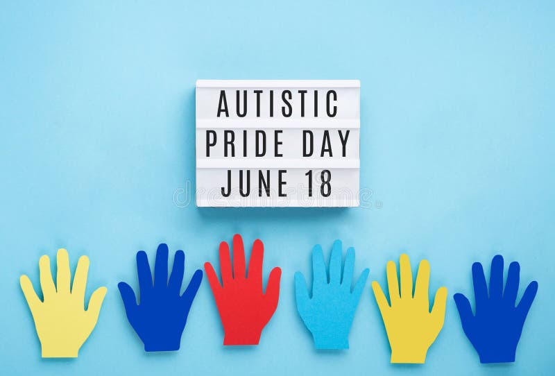 Autistic Pride Day, White Lightbox and Colorful Paper Hands on Blue Background Stock Photo