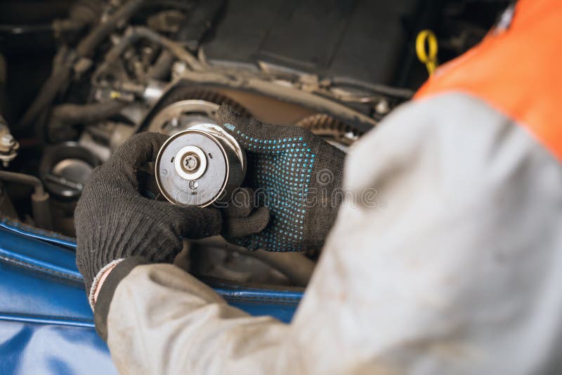 An auto mechanic checks the condition of the timing belt tensioner roller stock photography