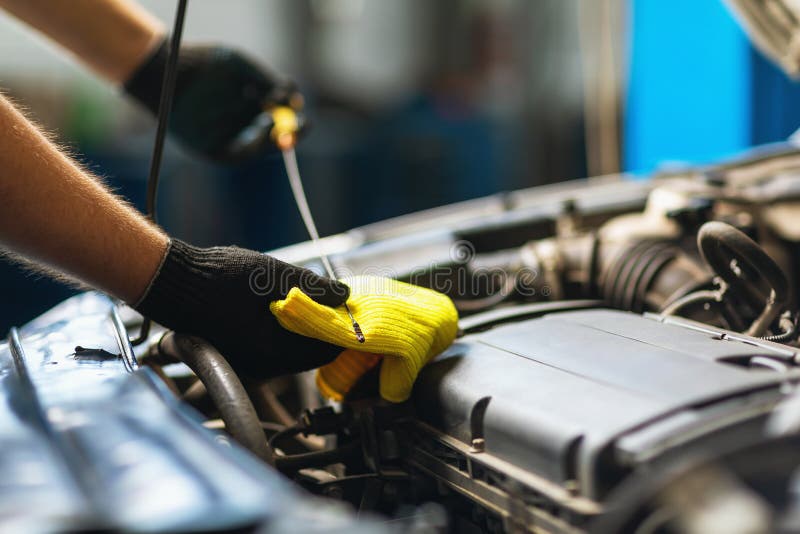 An Auto Mechanic Checks the Oil Level in a Car Engine with a Special