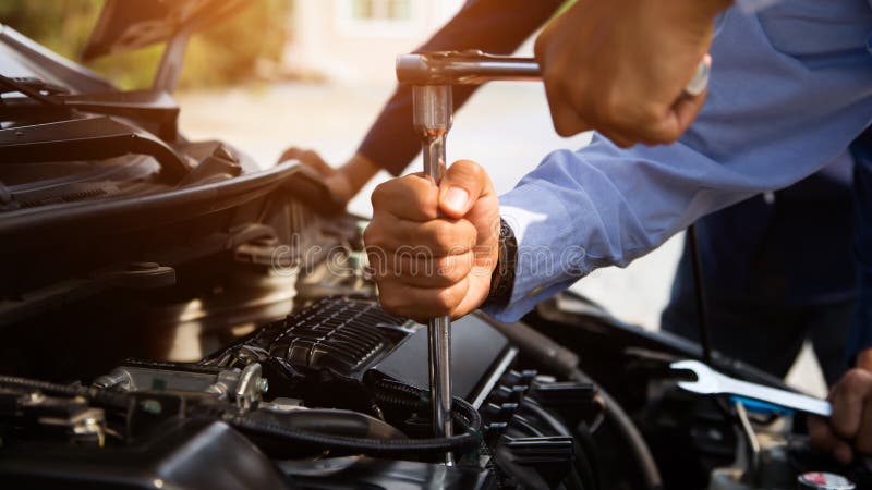 Mechaniker repariert auto in einer Werkstatt - Detail Hand mit Werkzeug  montiert im Motorraum // car repair in garage Stock Photo