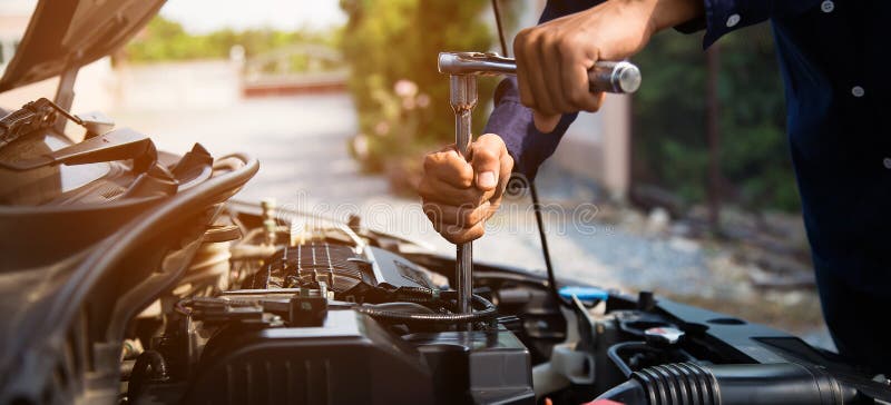 Auto mechanic hands using wrench to repair a car engine.