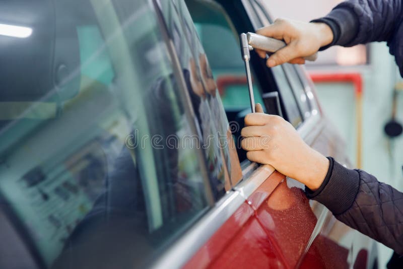 Auto mechanic removal of dents defects without painting on car body on service station.