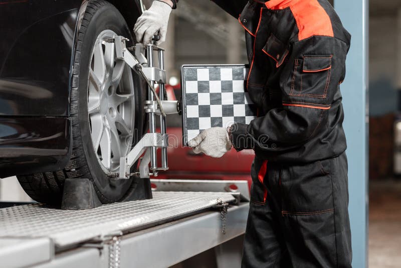 Auto Mechanic Sets the Car for Diagnostics and Configuration. Wheel Alignment Equipment on a Car