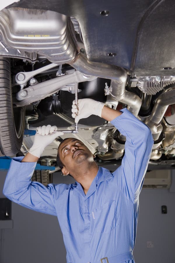 Meccanico Auto lavorare sotto la macchina in officina.