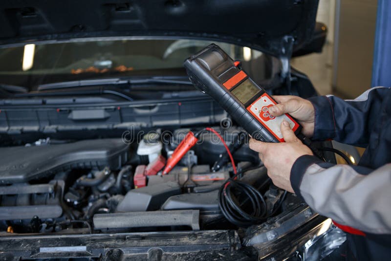 Auto mechanic uses multimeter voltmeter to check voltage level in car battery. royalty free stock photos Auto mechanic uses multimeter voltmeter to check voltage level in car battery. royalty free stock photos