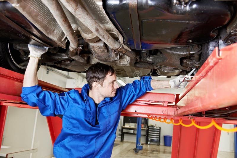 Auto mechanic at wheel alignment work with spanner