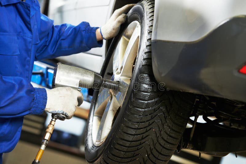 Auto mechanik śrubuje samochodowego koło wyrwaniem zdjęcia stock