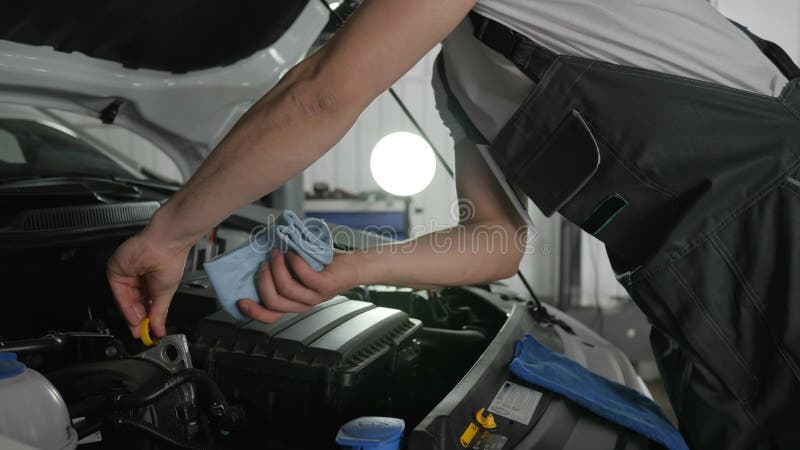 Auto mekaniker som kontrollerar den olje- nivån med den olje- oljestickan, diagnostiksystem maskin, bilservice, unga specialistre