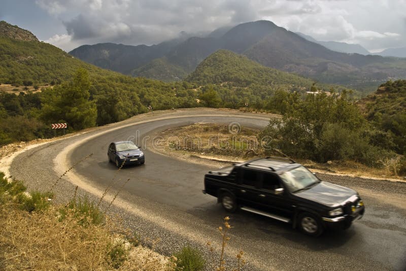 Auto's op een slingerende weg in de bergen stock fotografie