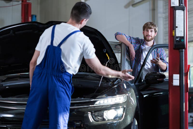 Image of young driver and auto service worker diagnosing car. Image of young driver and auto service worker diagnosing car