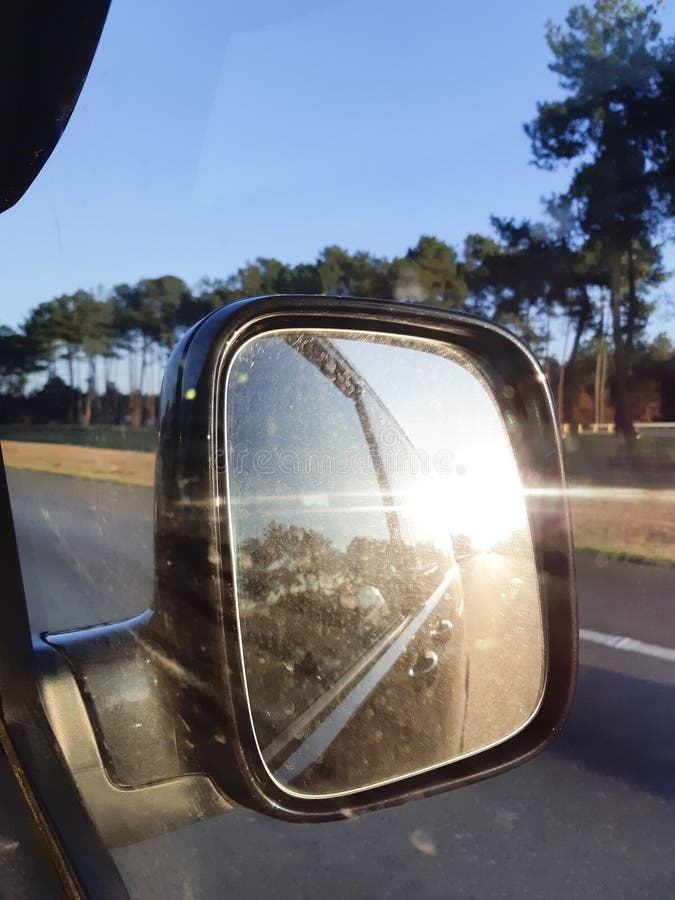 Autoachteruitkijkspiegel met de zomerzon en zonsondergang het nadenken royalty-vrije stock afbeelding Autoachteruitkijkspiegel met de zomerzon en zonsondergang het nadenken royalty-vrije stock afbeelding