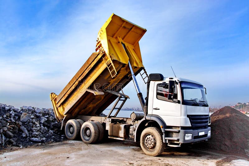 A dump truck is dumping gravel on an excavation site. A dump truck is dumping gravel on an excavation site