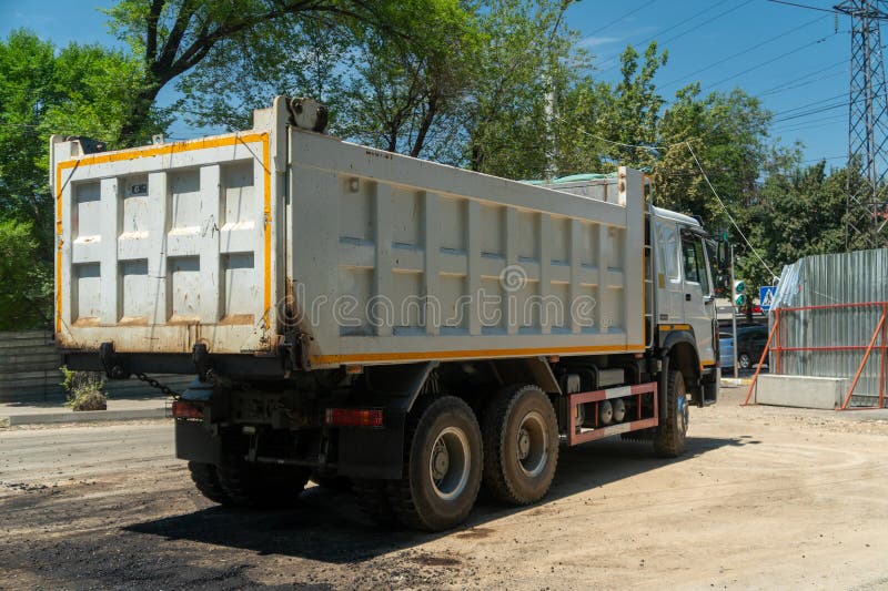 Autocarro a pompa posizionato nella zona di costruzione che fornisce asfalto per la riscoperta di pali per recinzioni e barriere d fotografia stock libera da diritti