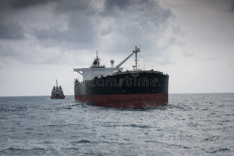 Crude oil tanker at open sea with offshore vessel tied up at astern underway to FPSO for loading cargo. Crude oil tanker at open sea with offshore vessel tied up at astern underway to FPSO for loading cargo