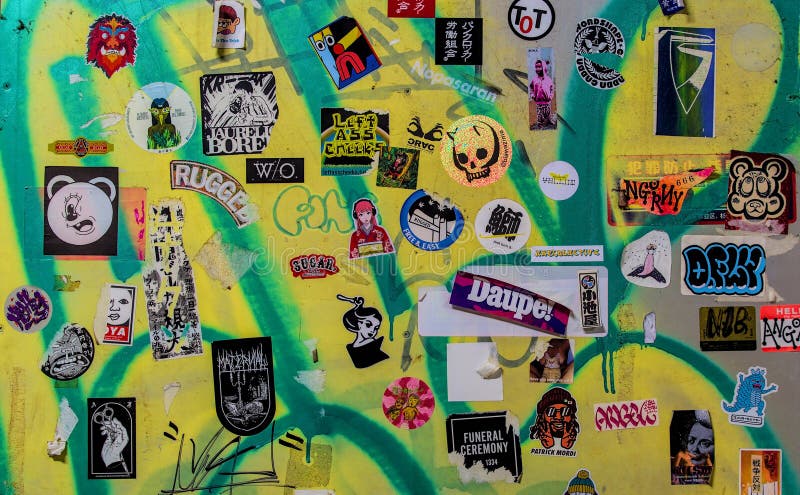 Autocolantes ecléticos numa parede coberta de graffiti fotos de stock royalty free