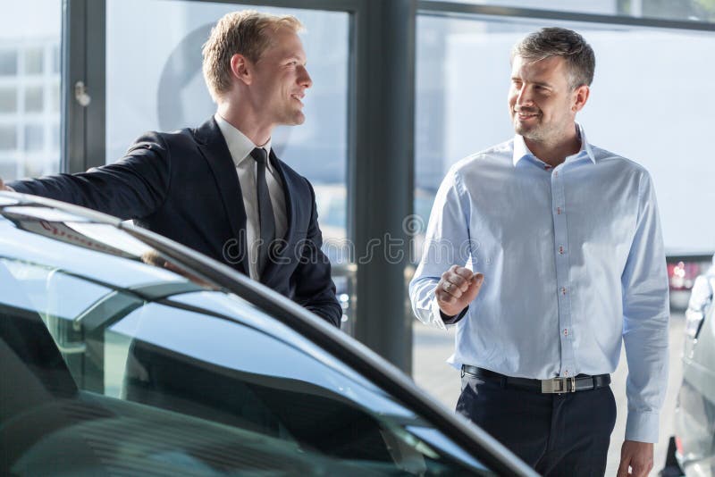 Autohändler, der Fahrzeug zeigt stockbild Autohändler, der Fahrzeug zeigt stockbild