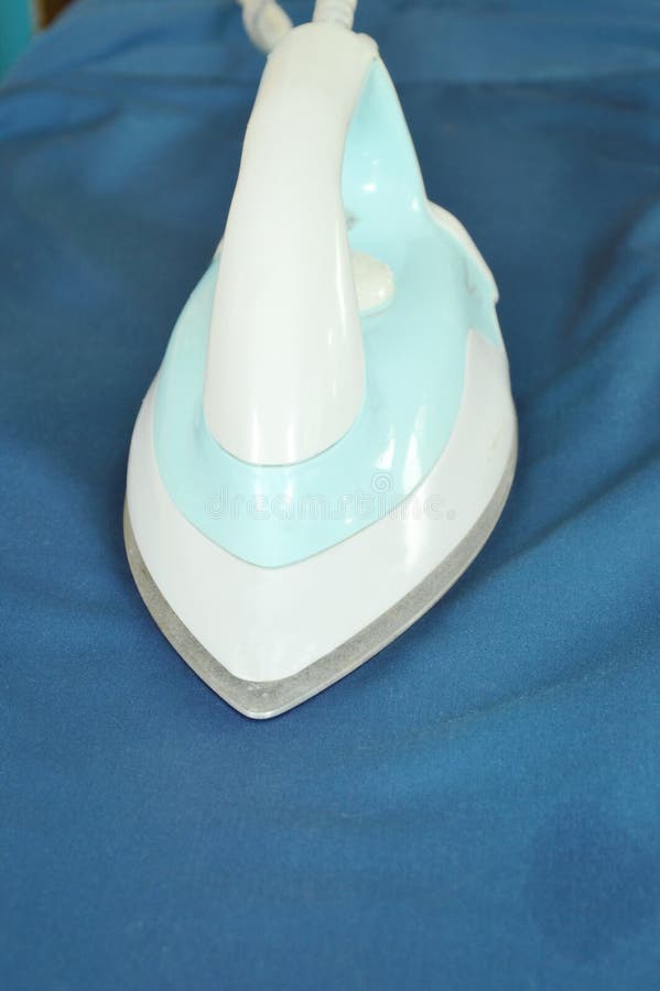 Automatic Electric Iron Pressing Cloth on Ironing Board Stock Photo