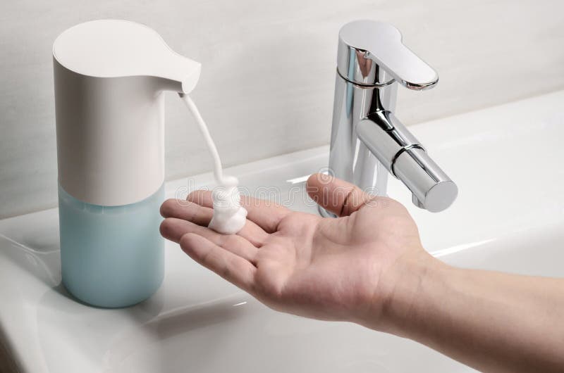 Automatic Soap Dispenser in the Bathroom. Hand with Soapy Solution