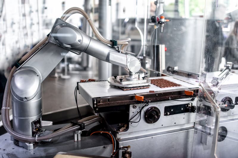 Automatische robotachtige hand die uiterst kleine beetjes van chocolade bewegen royalty-vrije stock fotografie Automatische robotachtige hand die uiterst kleine beetjes van chocolade bewegen royalty-vrije stock fotografie