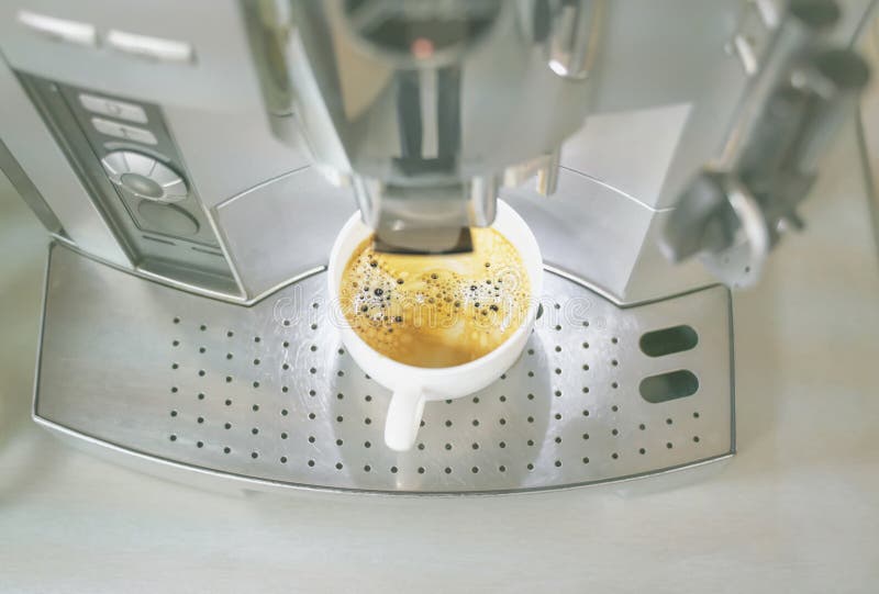 Automatyczna ekspres do kawy dostarczający filiżankę pysznej gorącej kawy aromatycznej do białego ceramicznego kubka zdjęcia stock