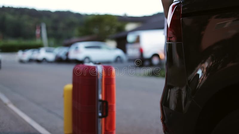 Automatyczny bagażnika otwarcie Mężczyzna stawia jaskrawe walizki w samochodzie