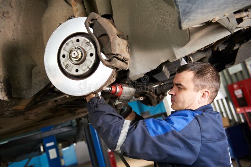 Automechaniker bei der Autosuspendierungsreparaturarbeit stockbild Automechaniker bei der Autosuspendierungsreparaturarbeit stockbild