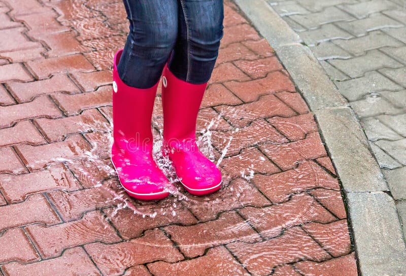 Automne Protection sous la pluie Fille portant les bottes en caoutchouc roses et sautant dans un magma photo stock Automne Protection sous la pluie Fille portant les bottes en caoutchouc roses et sautant dans un magma photo stock