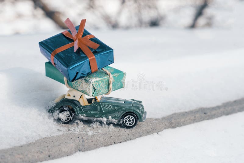Automobile d'annata del giocattolo all'aperto retro con i regali per il Natale ed il nuovo anno, automobile su una strada nevosa fotografie stock libere da diritti Automobile d'annata del giocattolo all'aperto retro con i regali per il Natale ed il nuovo anno, automobile su una strada nevosa fotografie stock libere da diritti