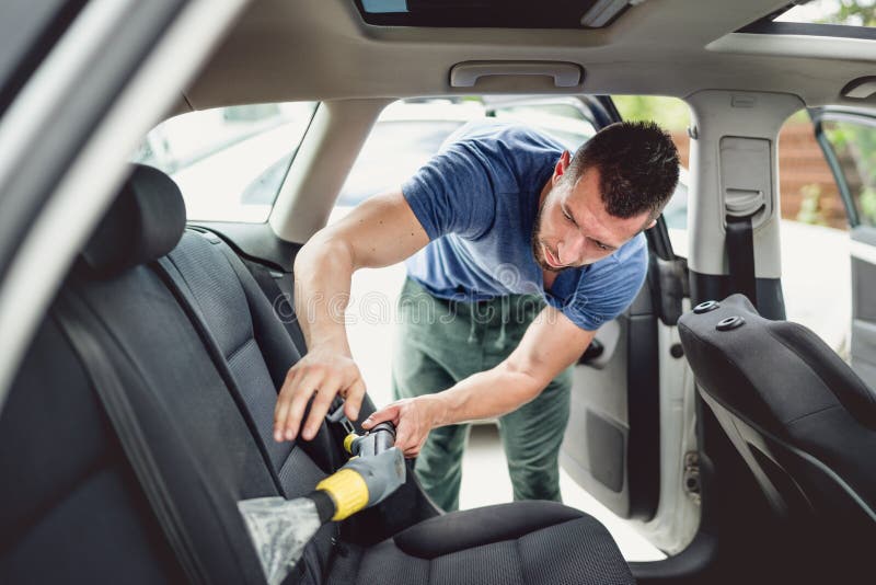 Professional worker vacuuming and cleaning automobile. Car care and detailing concept. Professional worker vacuuming and cleaning automobile. Car care and detailing concept