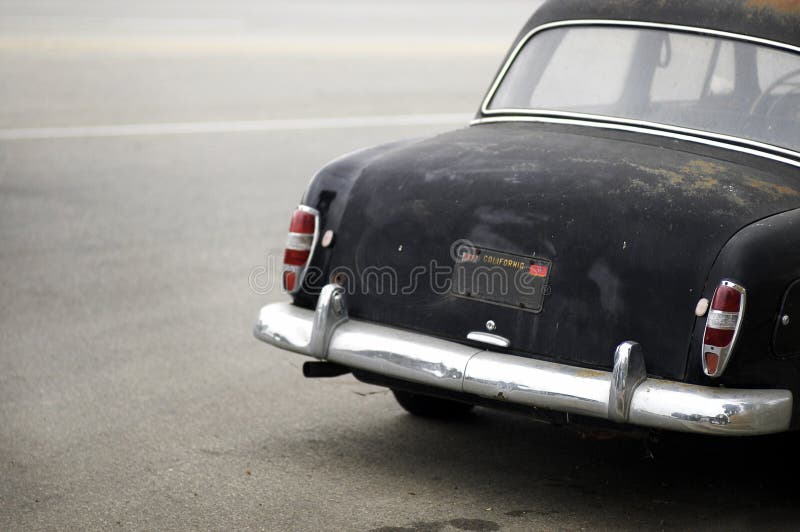 A large black german automobile from the early sixties parked on a California street, very rusty with shall Depth of Field with only foreground right in focus. A large black german automobile from the early sixties parked on a California street, very rusty with shall Depth of Field with only foreground right in focus
