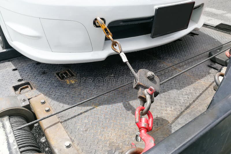 Automobile rimorchiata sul camion di rimorchio a base piatta con il gancio e la catena fotografia stock