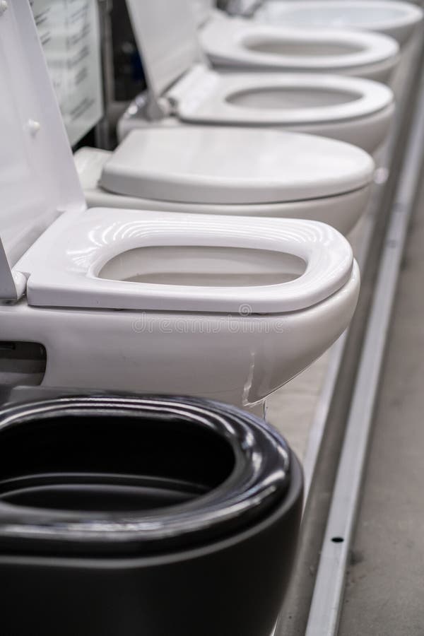 A row of grey automotive toilets are lined up in a store resembling automotive design elements such as bumpers, grilles, and hoods. A row of grey automotive toilets are lined up in a store resembling automotive design elements such as bumpers, grilles, and hoods