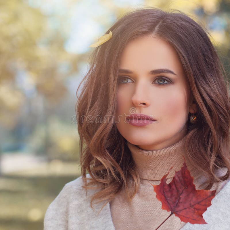 Autumn beauty. Young woman with fall leaves in wavy hair