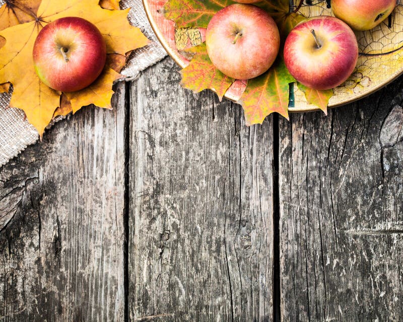 Autumn border from apples and fallen leaves on old wooden table. Autumn border from apples and fallen leaves on old wooden table