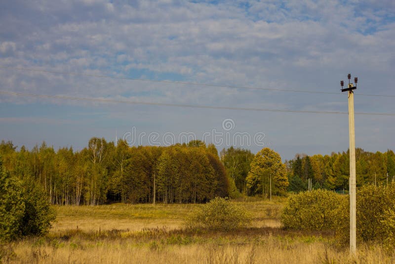 Autumn colorful landscape with views of the Russian field and forest. Electric pole on the background of yellow and orange trees stock photography Autumn colorful landscape with views of the Russian field and forest. Electric pole on the background of yellow and orange trees stock photography