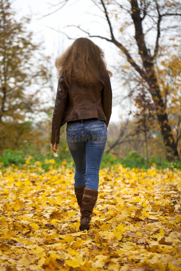 Autumn fashion image of young woman walking in the park