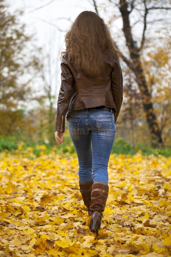 Autumn fashion image of young woman walking in the park