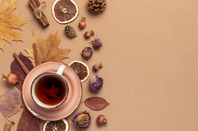 Autumn Flat lay composition. Cup of tea, autumn dry bright leaves, roses flowers, orange circle, cones, decorative pomegranate