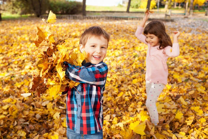 Image of boy and girl playing with autumn leaves in the park, shallow depth of field. Image of boy and girl playing with autumn leaves in the park, shallow depth of field