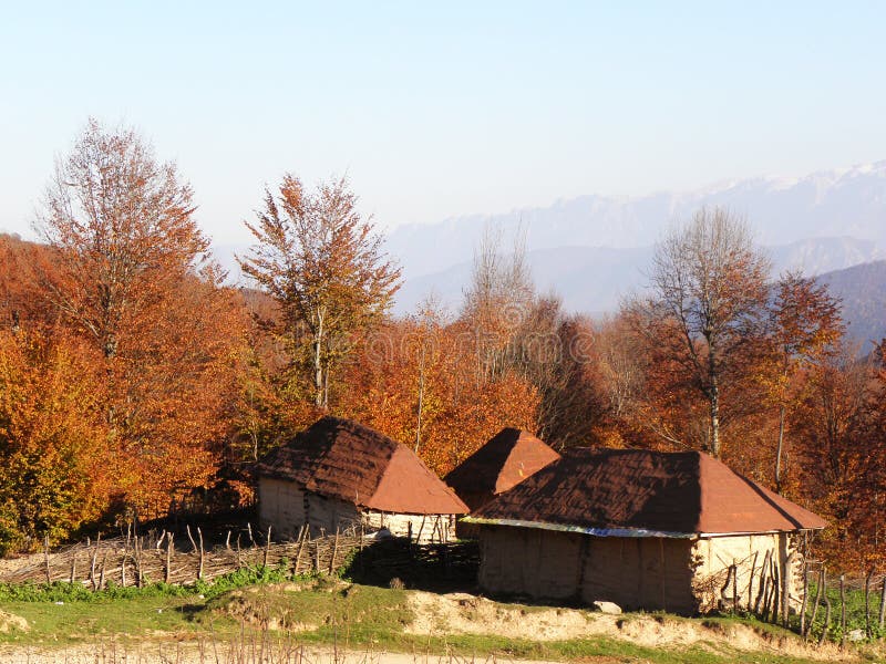 Autumn landscape in a beautiful mountain with colorful trees and a few old cottages with a red gable roof, northern cities of Iran