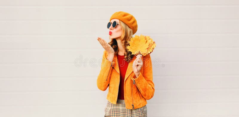 Autumn mood! woman with yellow maple leaves blowing red lips sending sweet air kiss over gray wall royalty free stock images Autumn mood! woman with yellow maple leaves blowing red lips sending sweet air kiss over gray wall royalty free stock images