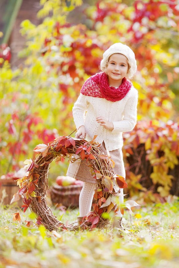 Autumn portrait of cute little girl. Pretty little girl with red grape leaves wreath in autumn park stock image Autumn portrait of cute little girl. Pretty little girl with red grape leaves wreath in autumn park stock image