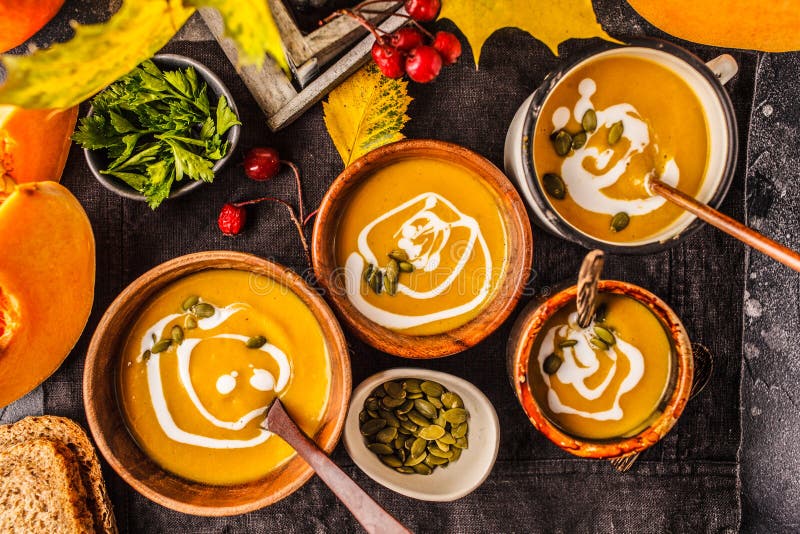 Autumn pumpkin soup puree with cream in cups, the autumn scenery. Healthy vegan food concept
