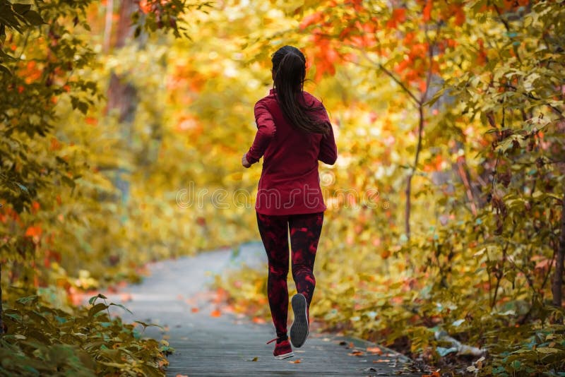 Autumn run active fit runner woman jogging in foliage forest woods of park, healthy living lifestyle exercising cardio