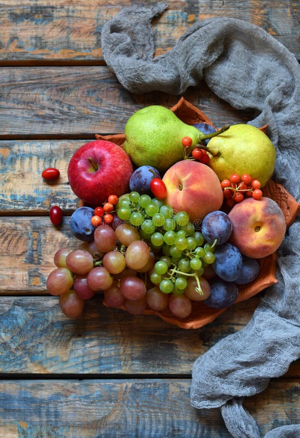 Autumn still life for thanksgiving with autumn fruits and berries on wooden background - grapes, apples, plums, viburnum, dogwood