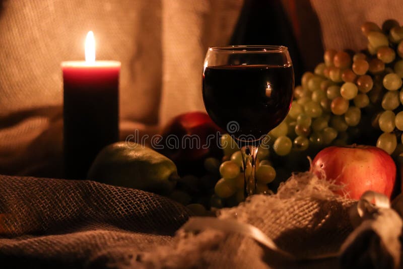 Autumn still life. Thanksgiving post card. Glass full of red wine with candle light reflection and fruits on background stock images Autumn still life. Thanksgiving post card. Glass full of red wine with candle light reflection and fruits on background stock images