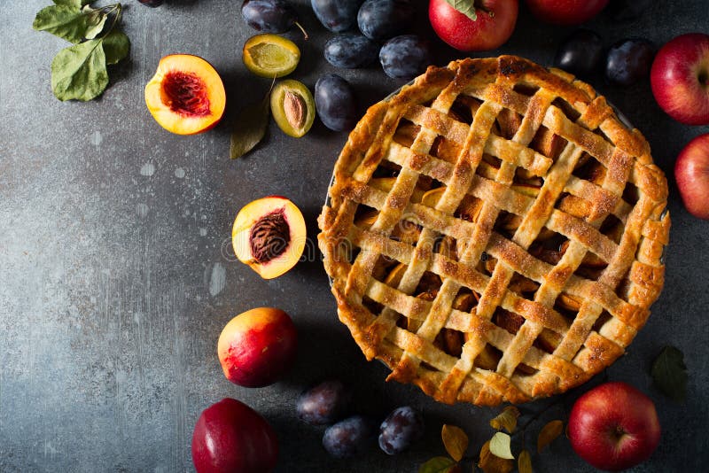 Autumn and summer pie with apple, peaches and plum on dark  background. Thanksgiving day table