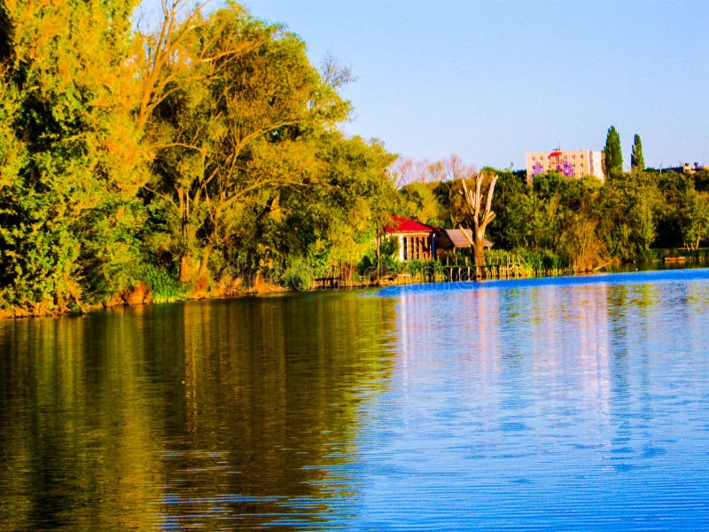 Autumn Evening Cityscape. Autumn sunny cloudless evening, a large calm lake, deciduous forest and a city on the shore of a large lake stock images Autumn Evening Cityscape. Autumn sunny cloudless evening, a large calm lake, deciduous forest and a city on the shore of a large lake stock images